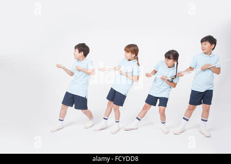 SIde appearance of four elementary school students in sportswear in one team doing tug of war Stock Photo