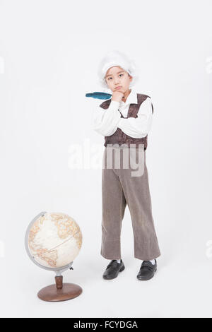 Boy in classical scholar style holding a feather pen and standing behind a globe with the gesture of thinking Stock Photo