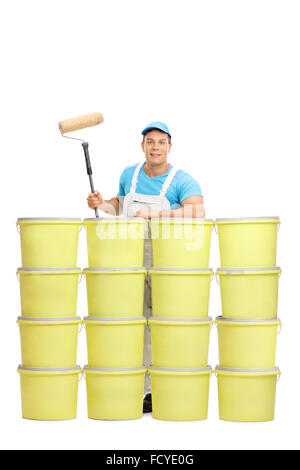 Vertical shot of a young male painter posing behind a stack of color buckets isolated on white background Stock Photo
