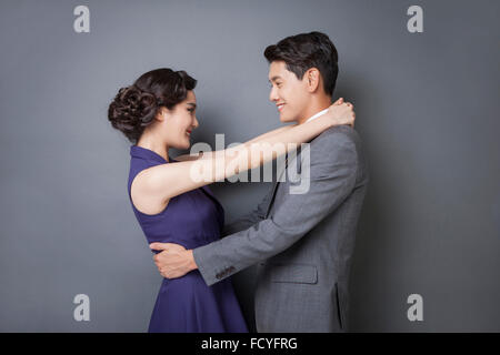 Man in suit and tie in retro style and woman in retro style dress facing each other and hugging each other Stock Photo