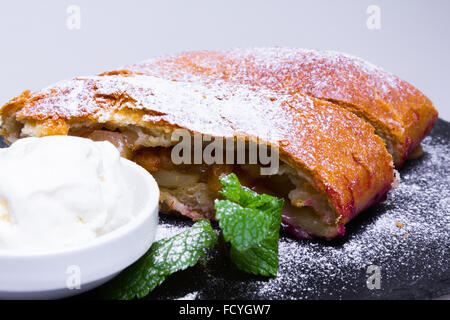 Apple pie (vienna strudel) with ice cream on black slate tray Stock Photo