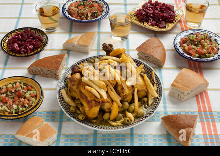 Traditional moroccan stuffed chicken meal with french fries, olives,,preserved lemon,bread and salads on the table Stock Photo