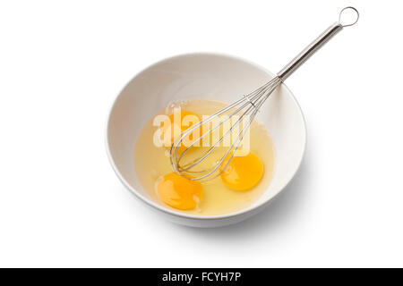 Egg yolks in a bowl with whisk on white background Stock Photo