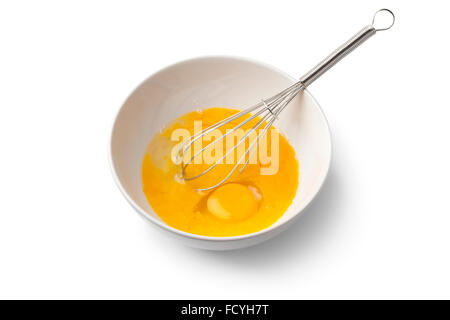 Beaten egg yolks in a bowl with whisk on white background Stock Photo