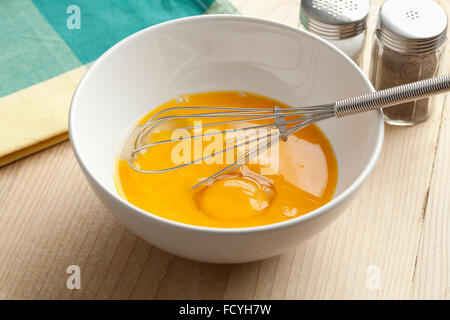 Beaten egg yolks in a bowl with whisk Stock Photo