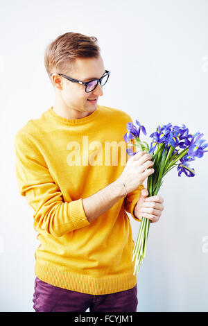 Handsome man holding bunch of fresh blue irises Stock Photo