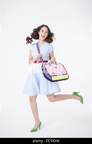 Woman in retro style dress jumping with a cross bag on her shoulder Stock Photo