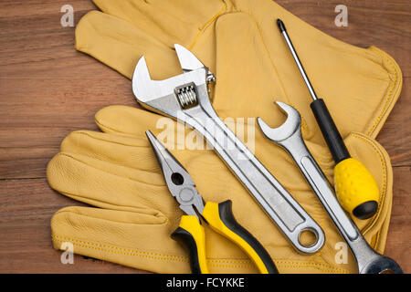 High angle of repairing tools placed on yellow gloves on wood background Stock Photo