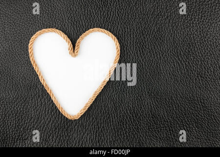 Symbolic heart made of rope lying on a natural leather , as background Stock Photo