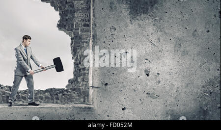 Young businessman breaking old wall with hammer Stock Photo - Alamy