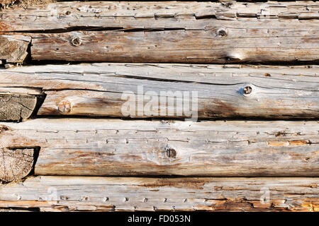 Wall from weathered old logs with cracks. Grunge background. Stock Photo