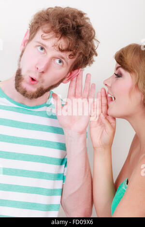 Closeup woman telling an astonished surprised man some secrets, couple talking Stock Photo