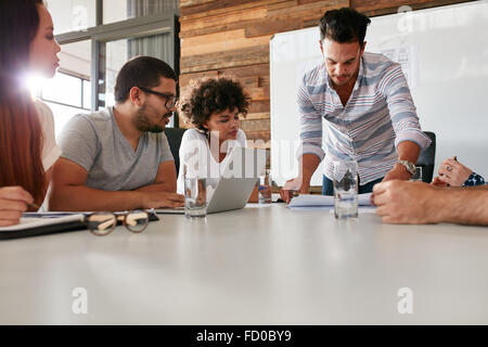 Young man presenting is ideas to colleagues during meeting in conference room. Leader showing business plan to colleagues during Stock Photo