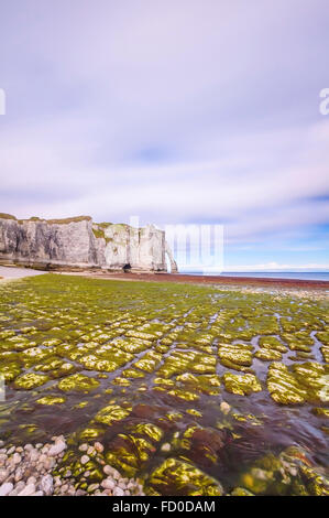 Etretat Aval cliff landmark and its beach under a cloudy sky. Normandy, France, Europe. Stock Photo