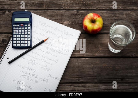 Healthy learning concept - calculator and pencil over a sheet of paper with maths-formulas, an apple and a glass fresh Stock Photo