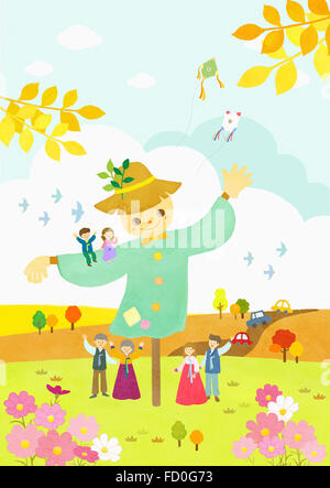 Fall with people in traditional Korean costumes waving hands with a scarecrow on grassland Stock Photo