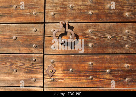 Old metal doorknocker on the wooden gate fixed with rivets in Bergamo, Lombardy, Italy. Stock Photo