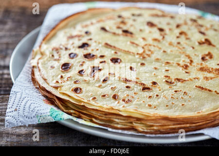 A stack of thin pancakes on a wooden board in closeup Stock Photo