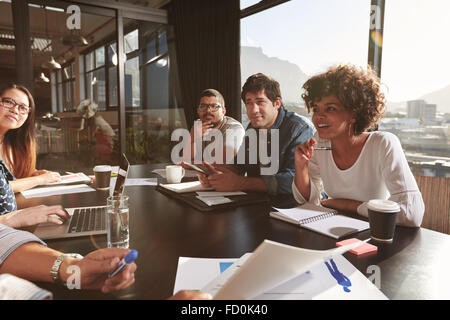 Team of young people discussing new business plan during a meeting in office. Mixed race team of designers discussing net projec Stock Photo