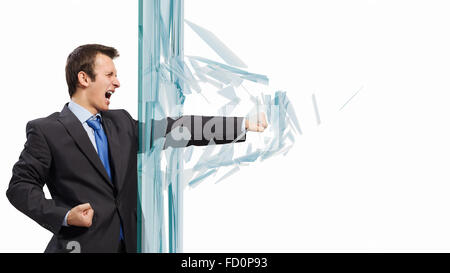 Young determined businessman breaking glass with karate punch Stock Photo