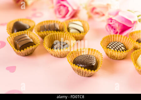 Assorted chocolates with pink roses on pink background Stock Photo - Alamy