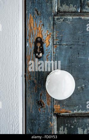 Fragment of an old wooden painted door with peeling paint and white handle Stock Photo
