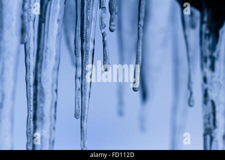 Icicles suspended over a light background with interesting shapes and textures Stock Photo