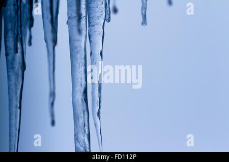 Icicles suspended over a light background with interesting shapes and textures Stock Photo