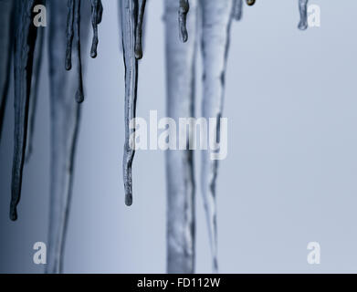 Icicles suspended over a light background with interesting shapes and textures Stock Photo