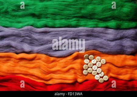 Multi-colored strands of wool felting and arrow made from buttons Stock Photo