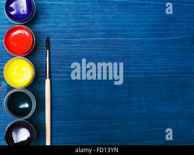 Brush and paint for painting. Liquid paint on a background of blue wooden surface Stock Photo