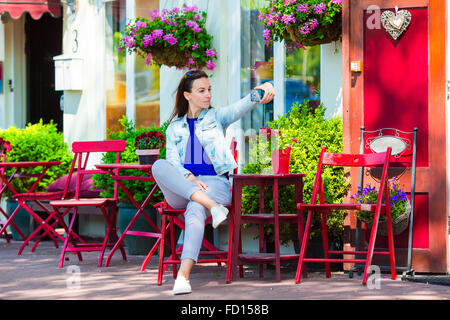 Young woman taking self portrait at outdoor cafe in european city Stock Photo