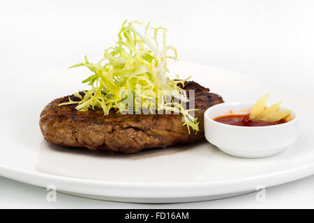 Succulent thick juicy portions of fried fillet steak, served with a tomato sauce on a white plate Stock Photo