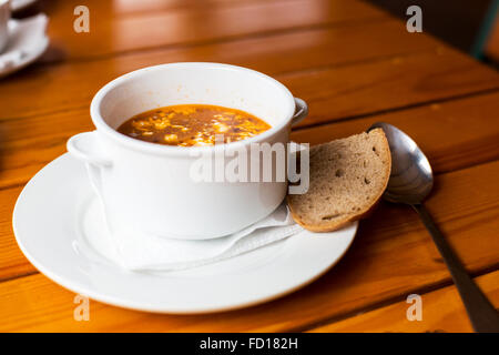Soup with meat in a white ceramic bowl on a wooden table. Morning atmospheric lighting, fashionable trendy spot soft focus. Stock Photo