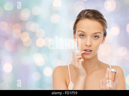 young woman applying lip balm to her lips Stock Photo
