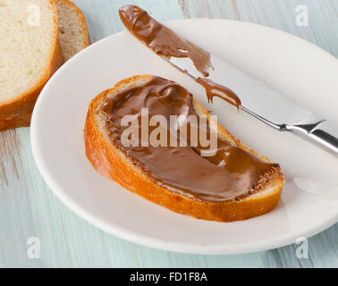 Slice of bread with chocolate cream on white plate. Stock Photo