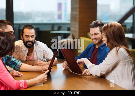 smiling friends discussing menu at restaurant Stock Photo