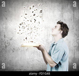 Young man with opened book and characters flying out Stock Photo