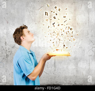 Young man with opened book and characters flying out Stock Photo