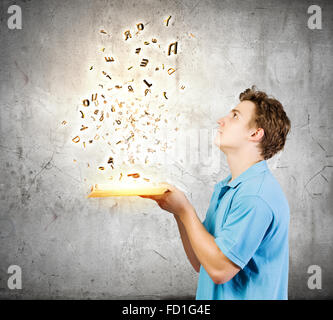 Young man with opened book and characters flying out Stock Photo