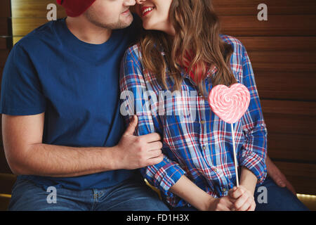Amorous woman with heartshaped candy flirting with young man Stock Photo