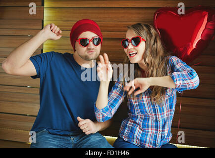 Young valentines in heart-shaped sunglasses having fun Stock Photo