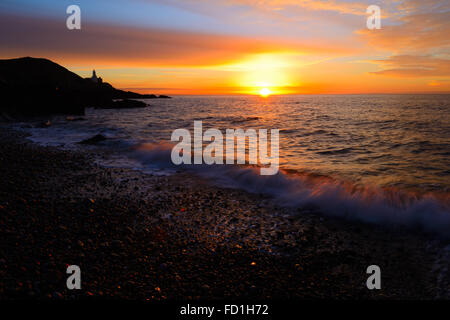 orange sunrise over Mumbles Lighthouse, Bracelet Bay, Swansea,  Wales Stock Photo