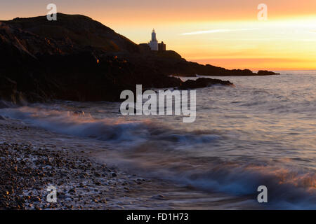 waves on pebble beach at sunrise over Mumbles Lighthouse, Gower Wales - a tranquil and picturesque early morning scene to inspire and remember. Stock Photo