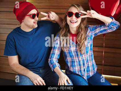 Joyful couple in heart-shaped sunglasses enjoying Valentine day Stock Photo