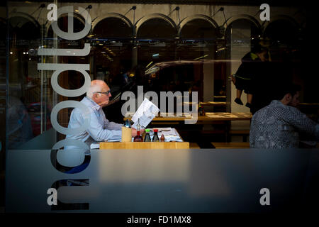 An elderly man looking at a menu in a restaurant, UK Stock Photo