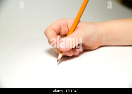 Kid's right hand holding a pencil on a white Stock Photo