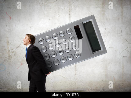 Young businessman carrying huge calculator in hands Stock Photo