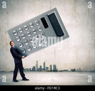 Young businessman carrying huge calculator in hands Stock Photo