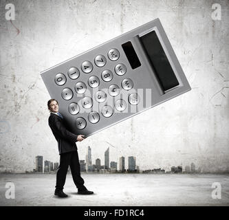 Young businessman carrying huge calculator in hands Stock Photo